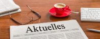 Zeitung auf Schreibtisch - Aktuelles Eine Zeitung mit der Aufschrift "Aktuelles" auf einem Tisch mit Kaffeetasse und Lesebrille.