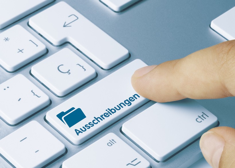 Ausschreibungen Ein Finger drückt eine Taste auf der Tastatur mit der Aufschrift "Ausschreibungen"