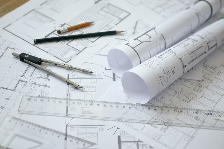 Zirkel, Stifte und Lineal auf einem Bauplan.
