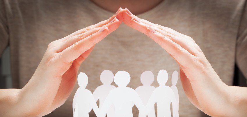 Gemeinschaft in Sicherheit Papiermenschen unter beschützenden Händen