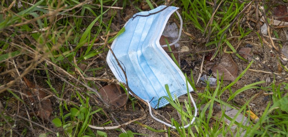 Eine benutzte Einwegmaske im Gras.