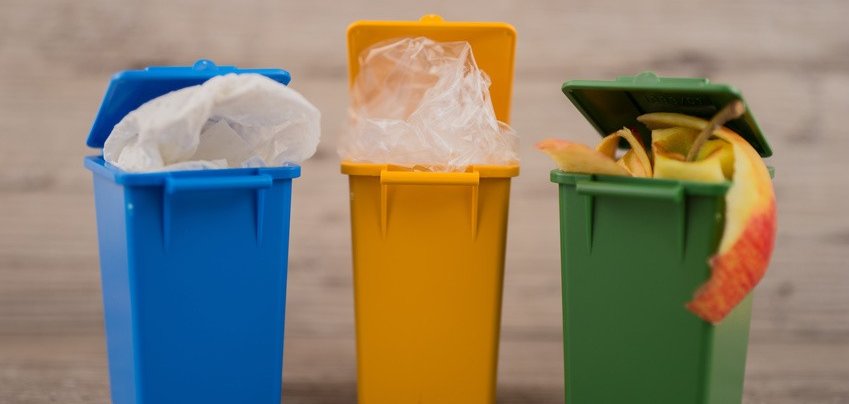 Drei verschiedenfarbige Mülltonnen.