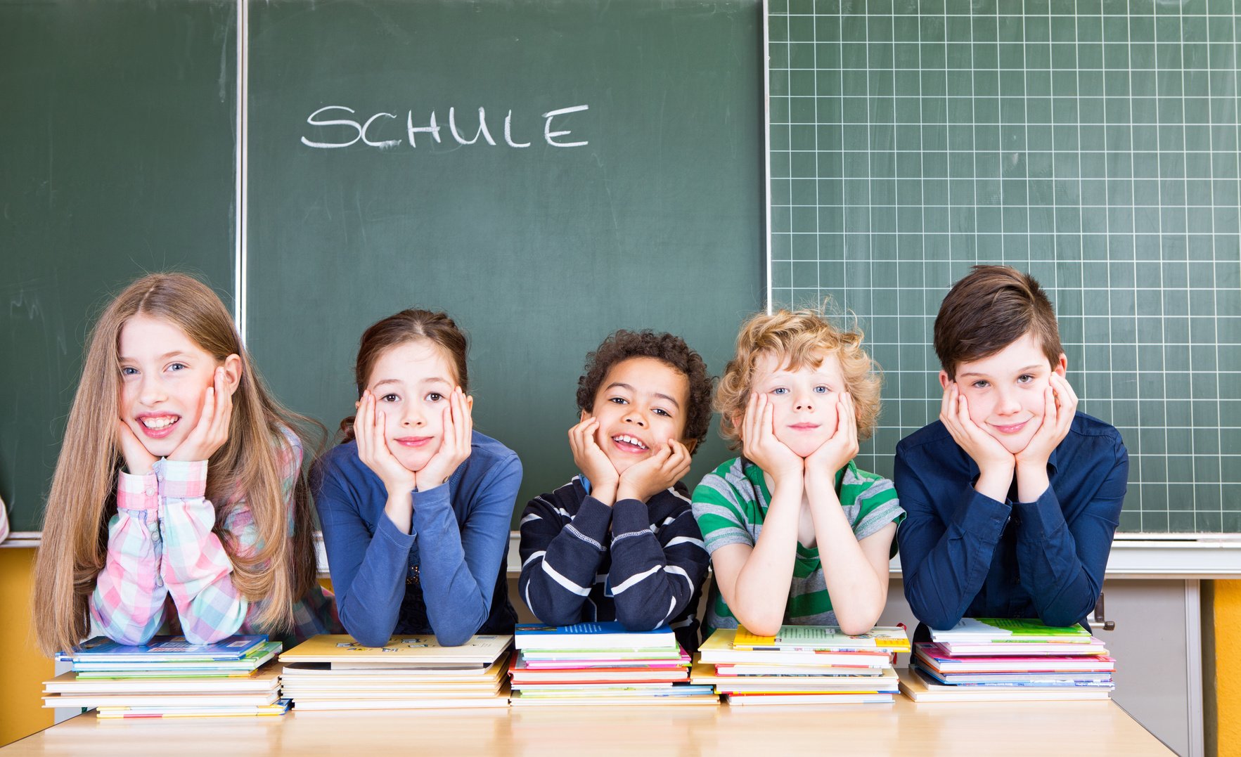 Schüler sitzen am Lehrertisch vor der Tafel.