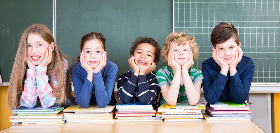 Schüler sitzen am Lehrertisch vor der Tafel.