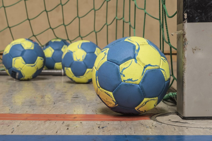 Handball Mehrere blaue Handbälle auf dem Boden einer Sporthalle.