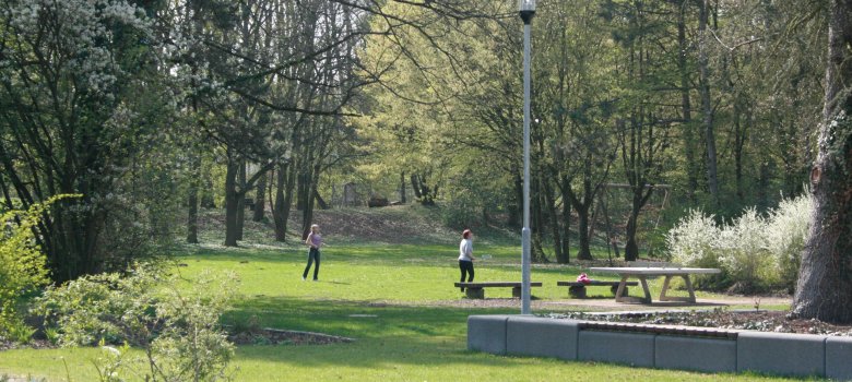 Zwei Badminton-spielende Personen auf einer großen, sonnigen Grünfläche des Freizeitparks.