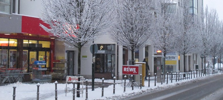 Im Vordergrund ist das Schild für einen Supermarkt zu sehen, dahinter beginnt die Galeriepassage