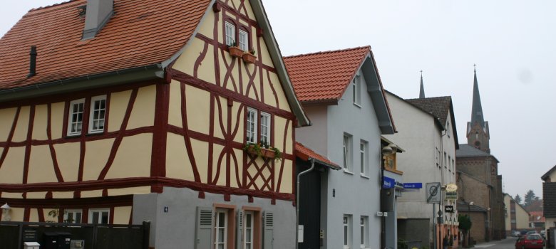 Eine Häuserreihe mit Fachwerkhaus im Vordergrund, hinten sind die Türme der katholischen Kirche zu sehen.