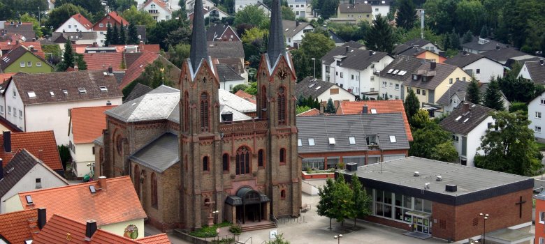 St. Vitus und Gemeindehaus Die St. Vitus Kirche ist leicht von oben zu sehen, daneben das flache Gebäude des Gemeindehauses.