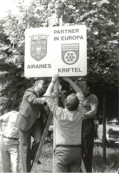 Ein Schild wird aufgehängt, das die Städzepartnerschaft mit Airaines festhält.