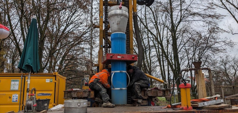 Arbeiter führen ein Rohr in den neu gebohrten Brunnenschacht ein.
