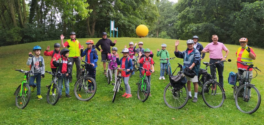 Zehn Kinder mit ihren Fahrrädern und Betreuern vom Partnerschaftsverein vor der Sonnen-Nachbildung im Freizeitpark.