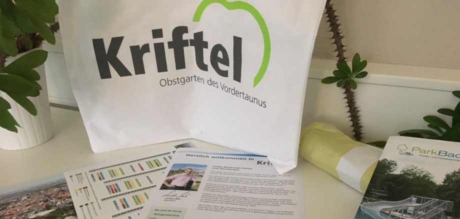 Der neue Einkaufsbeutel mit Kriftel-Logo und davor Imagebroschüre, Abfallkalender und Neubürgerbrief.