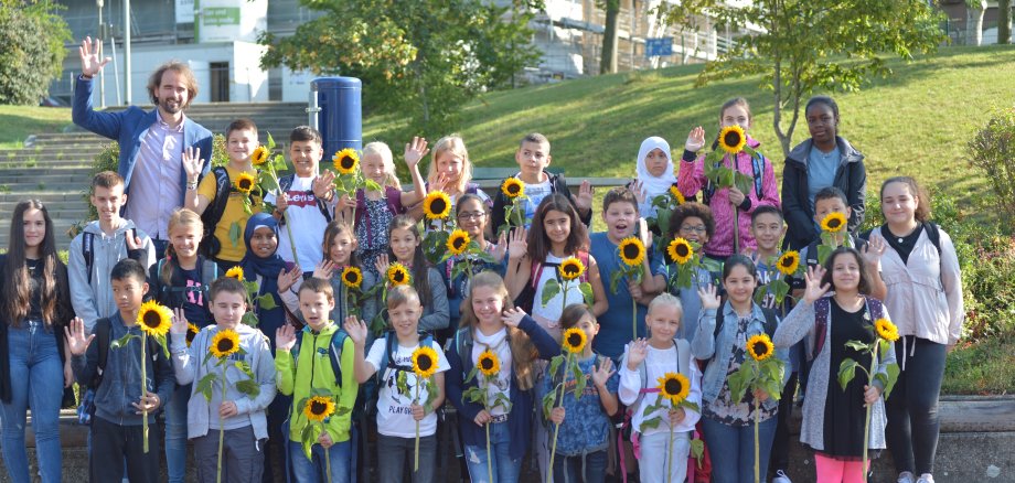 Die Klasse R5a mit Lehrer Ivo Reichert. Alle Schüler haben Sonnenblumen in der Hand.