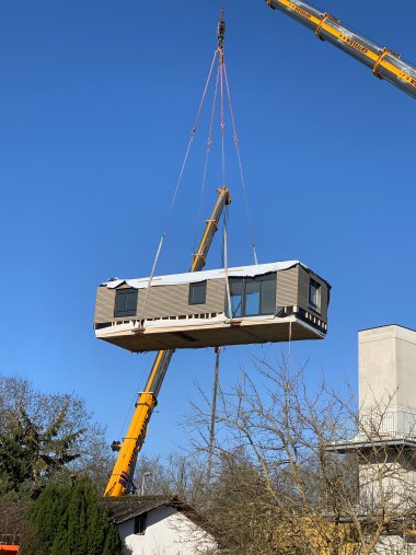 Ein am Kran schwebendes Holzmodul.
