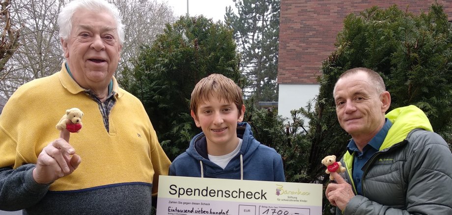 Bernhard Daubitz übergibt mit seinem Enkel den Spendenscheck an einen Vertreter von Bärenherz.