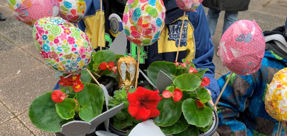 Ein Kind mit Blumen und bunt beklebten Ostereiern.