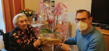 Bürgermeister Seitz übergibt der Jubilarin Blumen.