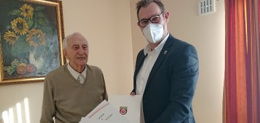 Bürgermeister überreicht dem Jubilar Urkunden.