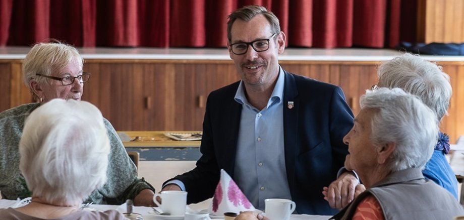 Bürgermeister Seitz schunkelt mit Senioren zur Musik.