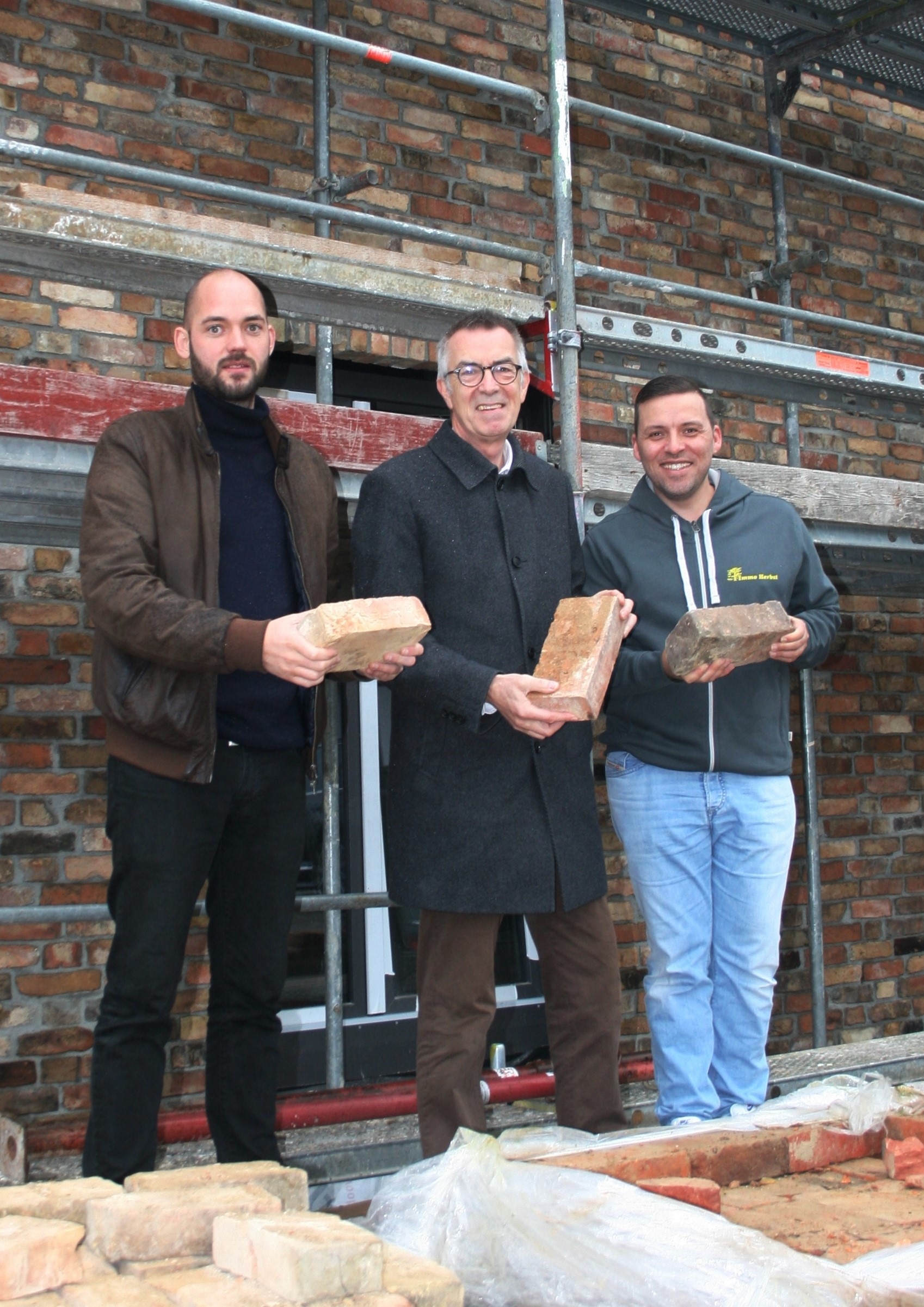 Franz Jirasek mit Architekt vor dem Neubau auf dem Gelände der Alten Ziegelei. Sie halten alte Krifteler Ziegel in der Hand.