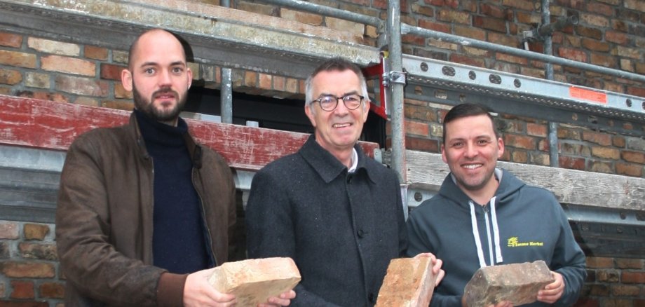 Franz Jirasek mit Architekt vor dem Neubau auf dem Gelände der Alten Ziegelei. Sie halten alte Krifteler Ziegel in der Hand.