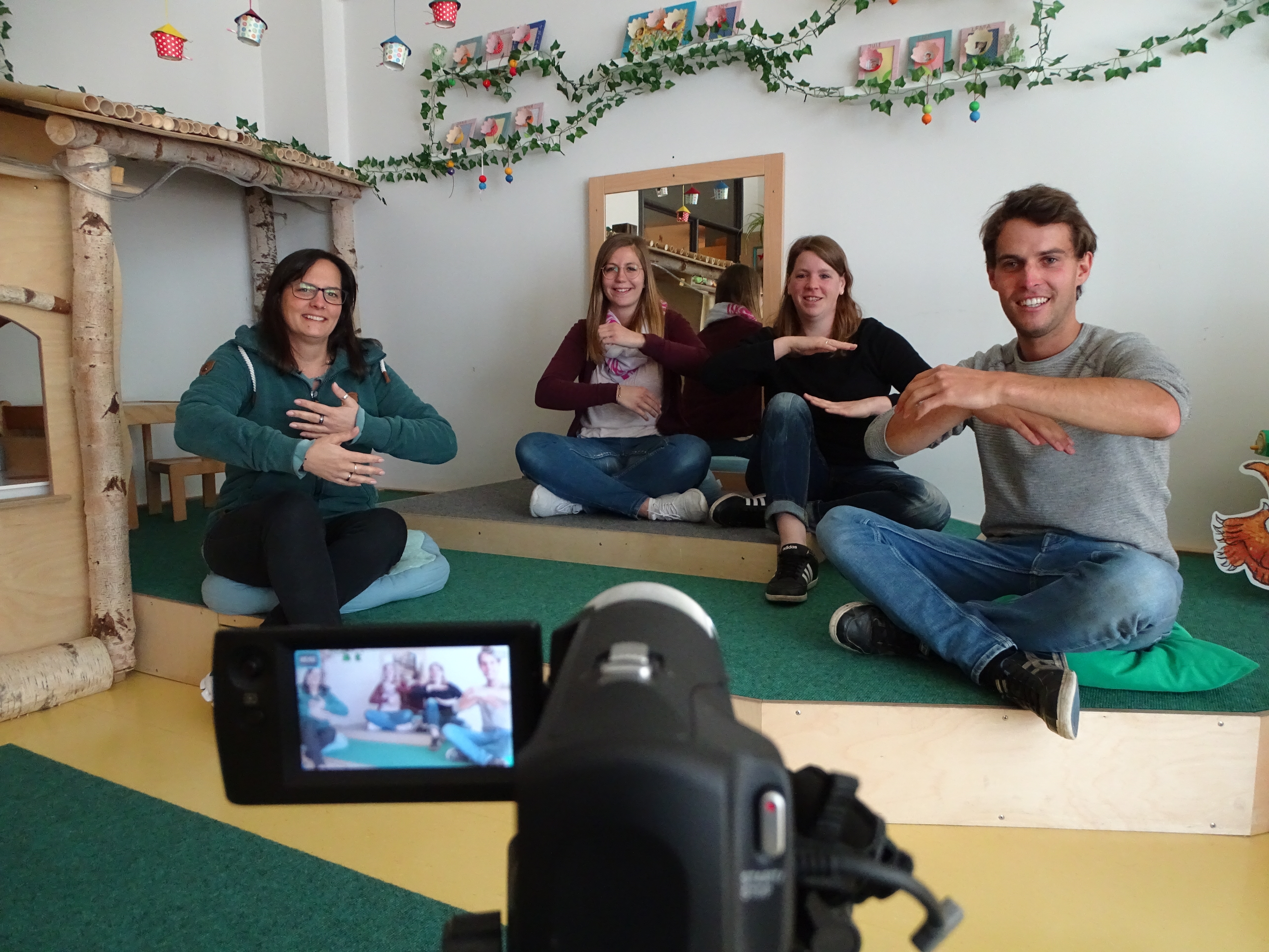 Vier Erzieher der Kita Vogelnest hinter einer Filmkamera. Sie singen ein Lied für ihre Kitakinder.