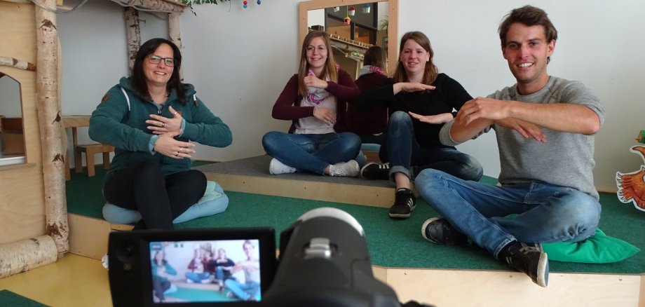 Vier Erzieher der Kita Vogelnest hinter einer Filmkamera. Sie singen ein Lied für ihre Kitakinder.