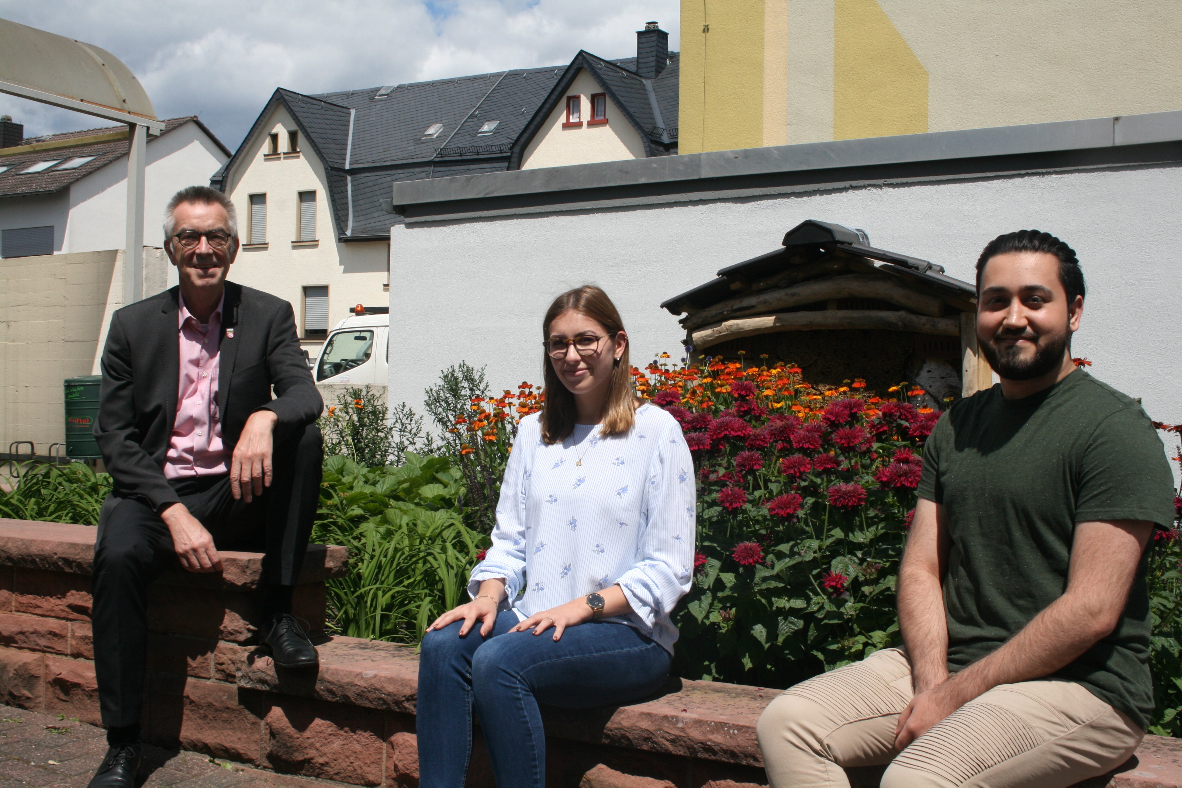 Die ehemaligen Azubis Celia Volk und Naif Mardin mit Franz Jirasek vor dem Bienenbeet am Bauamt.
