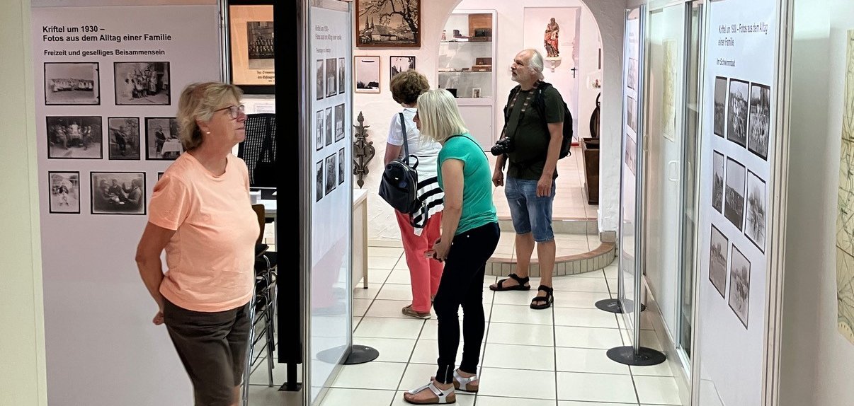 Besucherinnen und Besucher schauen sich Fotos an.