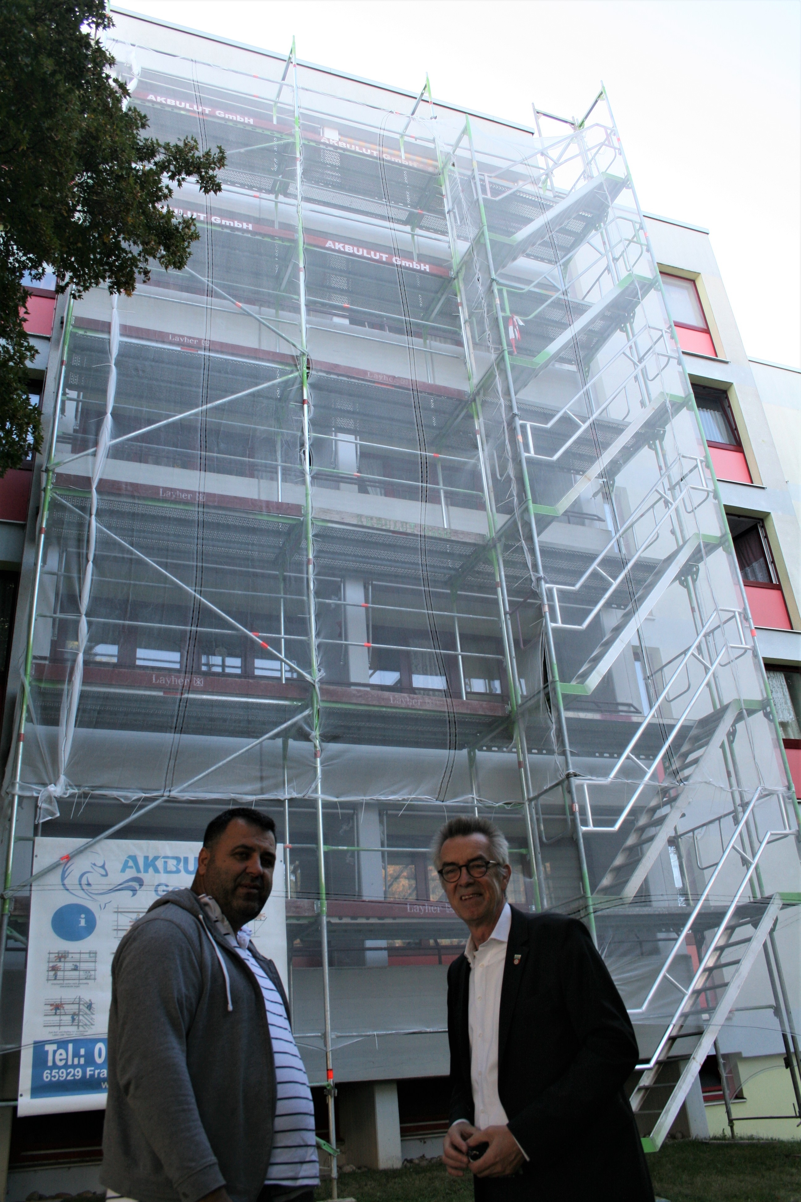 Franz Jirasek mit dem Bauleiter vor dem Josef-Wittwer-Haus. Die Balkone sind eingerüstet.