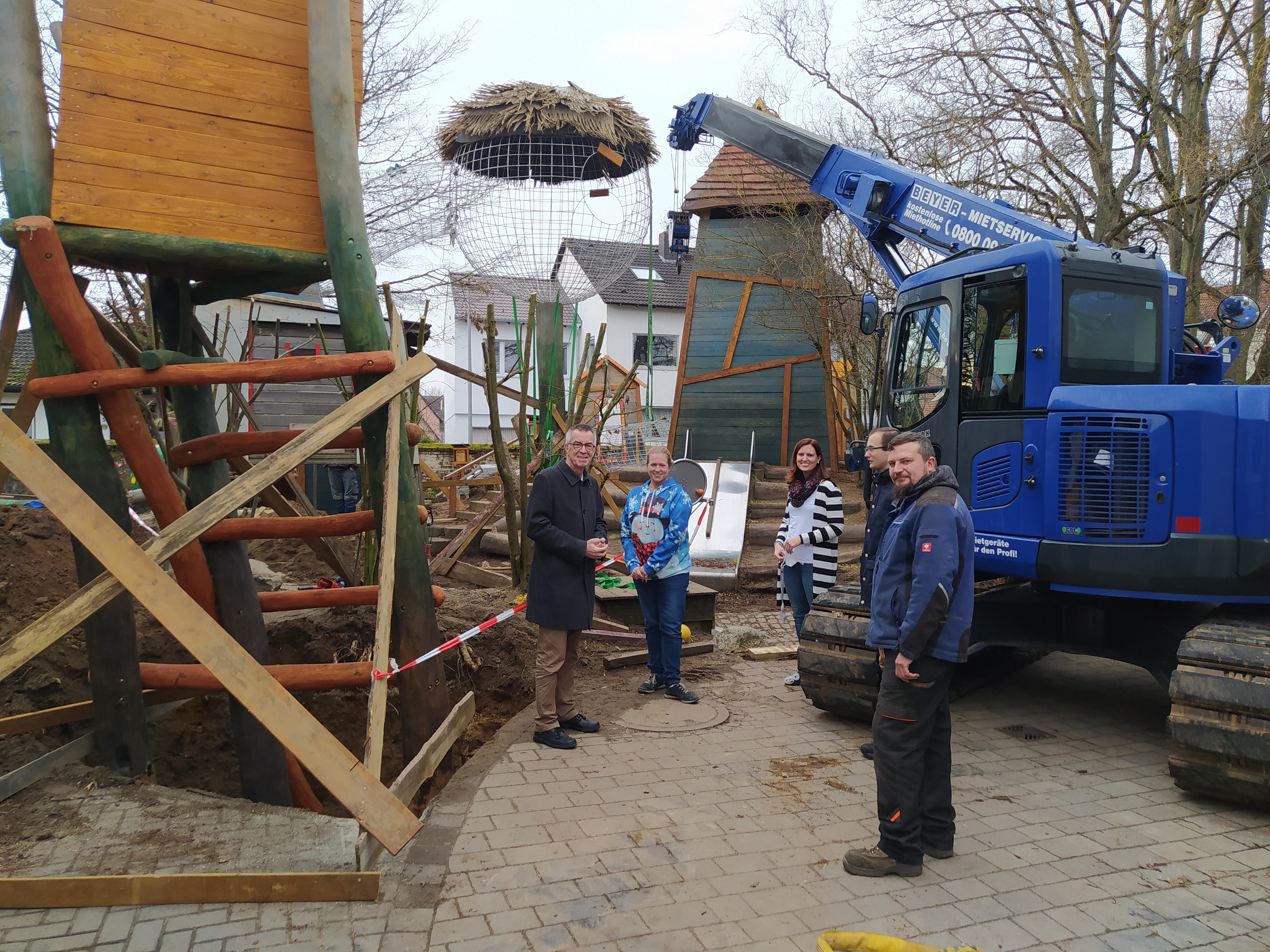 Franz Jirasek und die Leitung der Kita Vogelnest vor dem Baumhaus-Park auf dem Kita-Gelände.