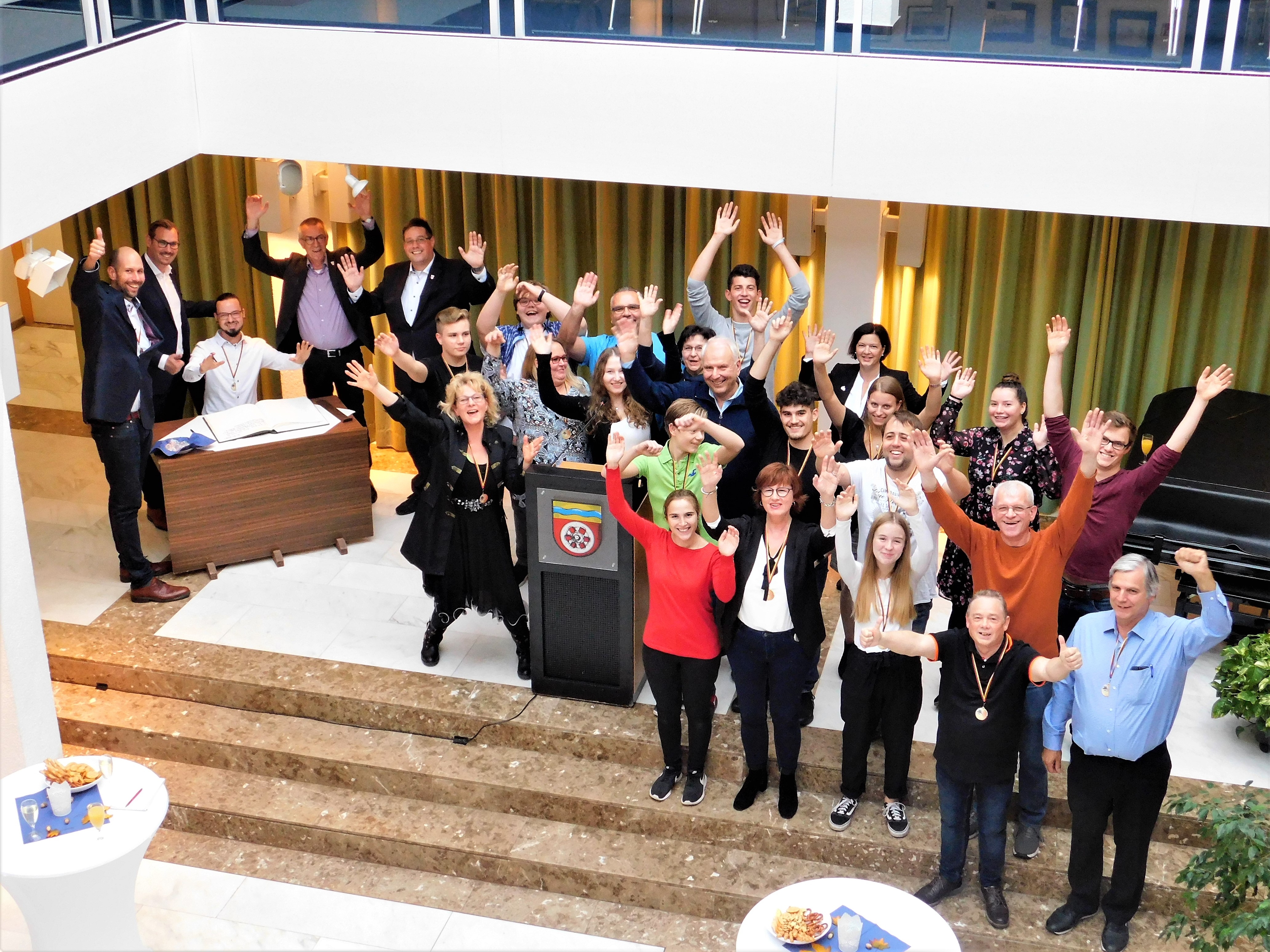 Die jubelnden Musiker winken in die Kamera.