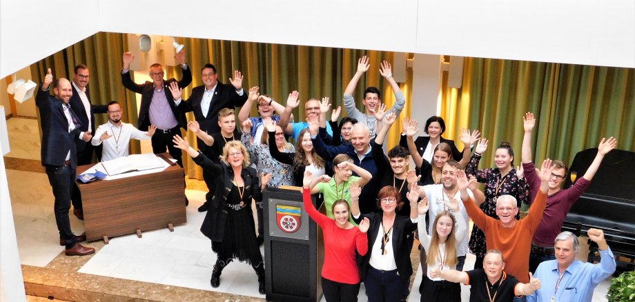 Die jubelnden Musiker winken in die Kamera.
