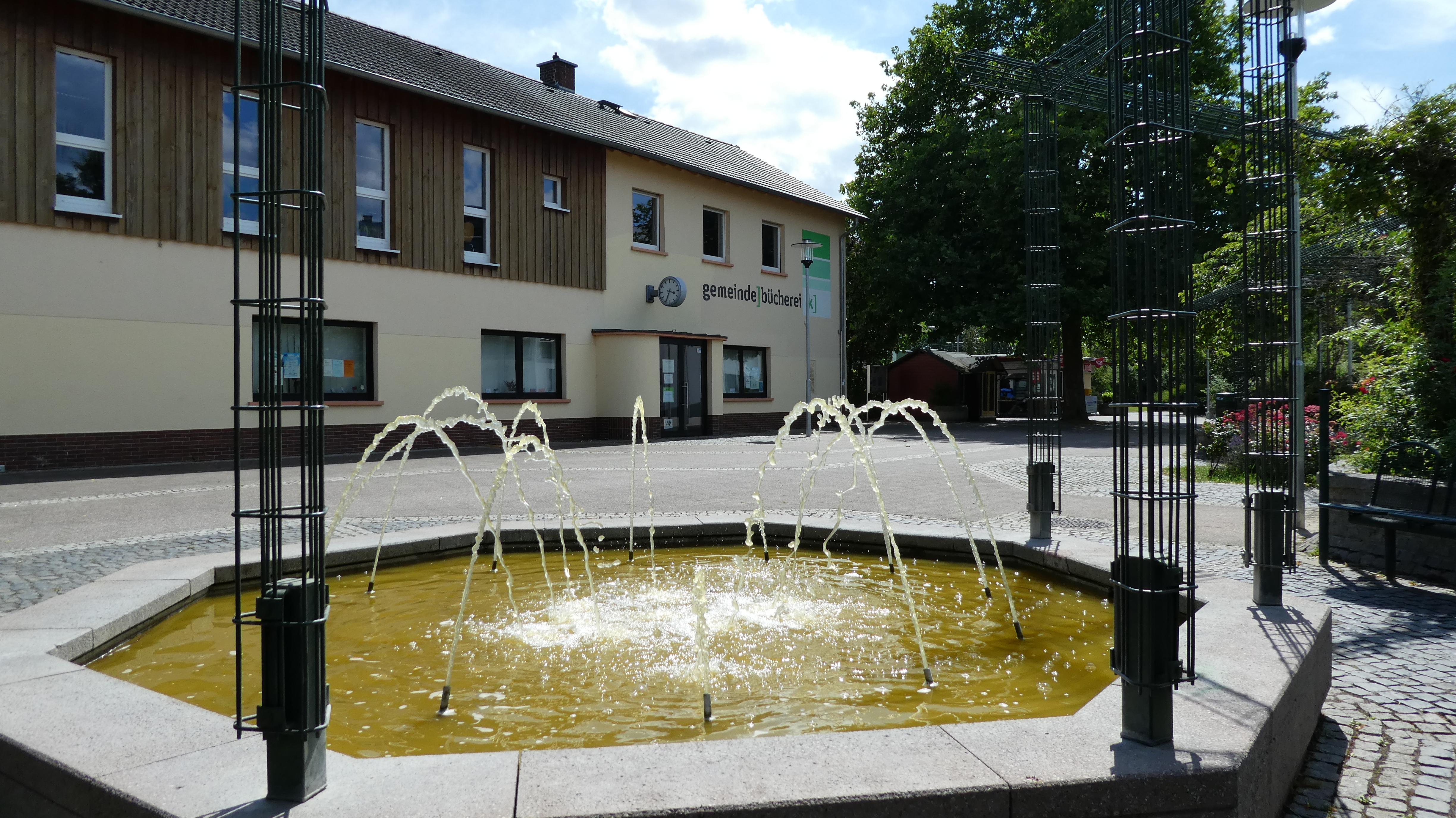 Die Gemeindebücherei mit dem Brunnen im Vordergrund.