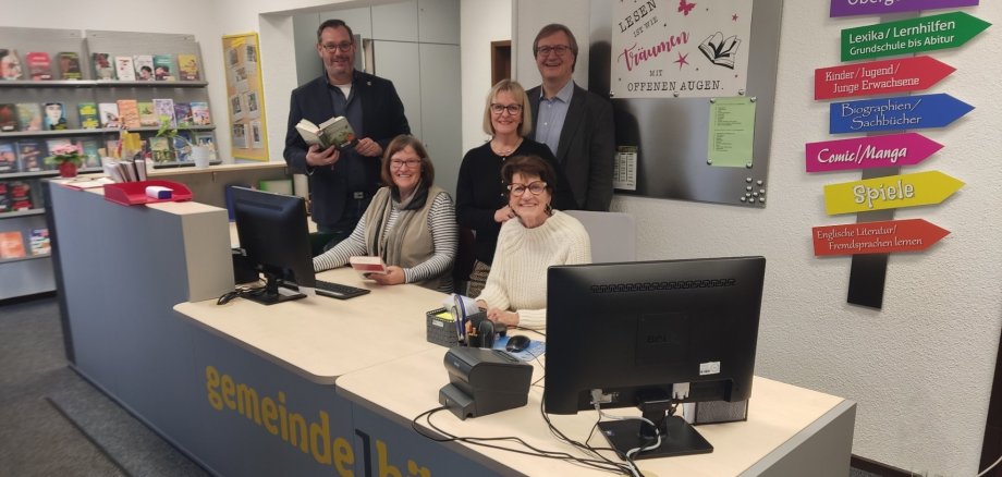 Bürgermeister und Büchereiteam hinter der neuen Theke.