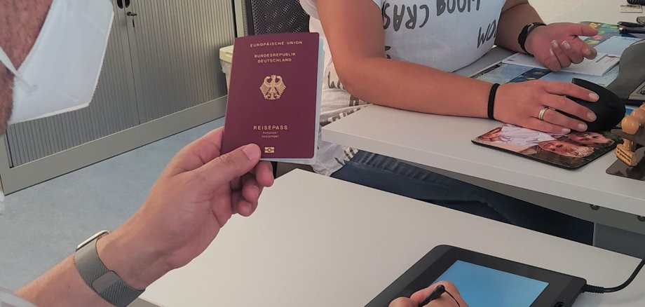 Bürgermeister Seitz mit einem Pass in der Hand am neuen Arbeitsplatz.