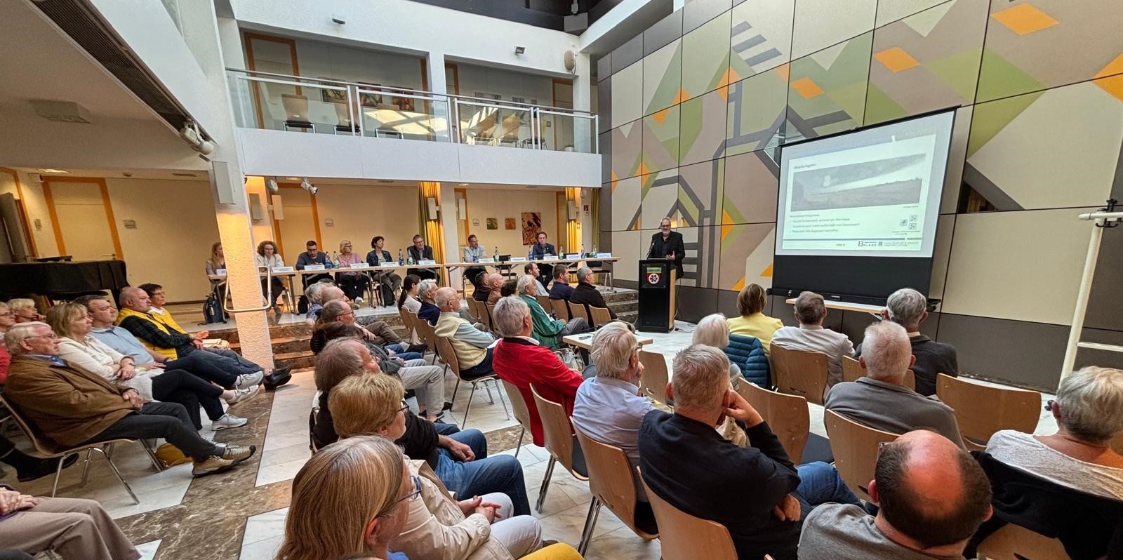 Zuhörer und Referent im Rathausfoyer.