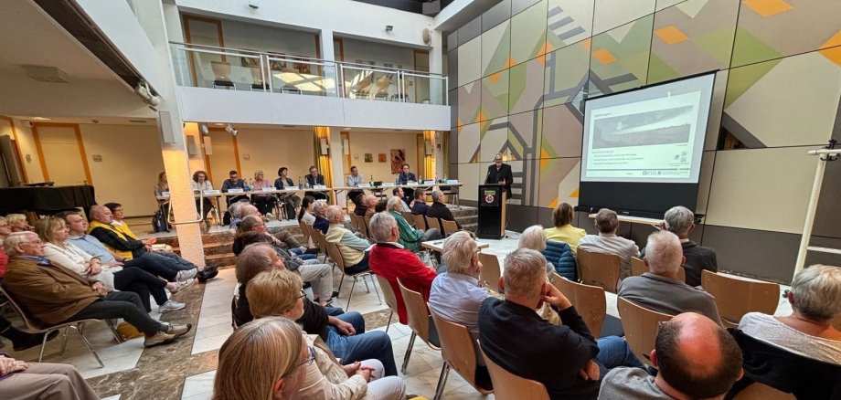 Zuhörer und Referent im Rathausfoyer.