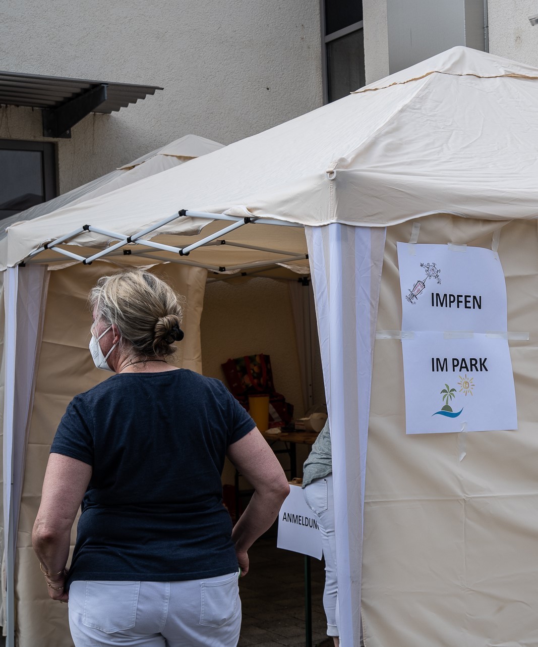 Eine Frau mit Maske vor einem Zelt.