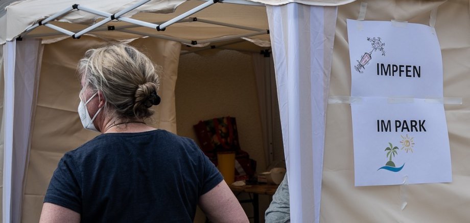 Eine Frau mit Maske vor einem Zelt.