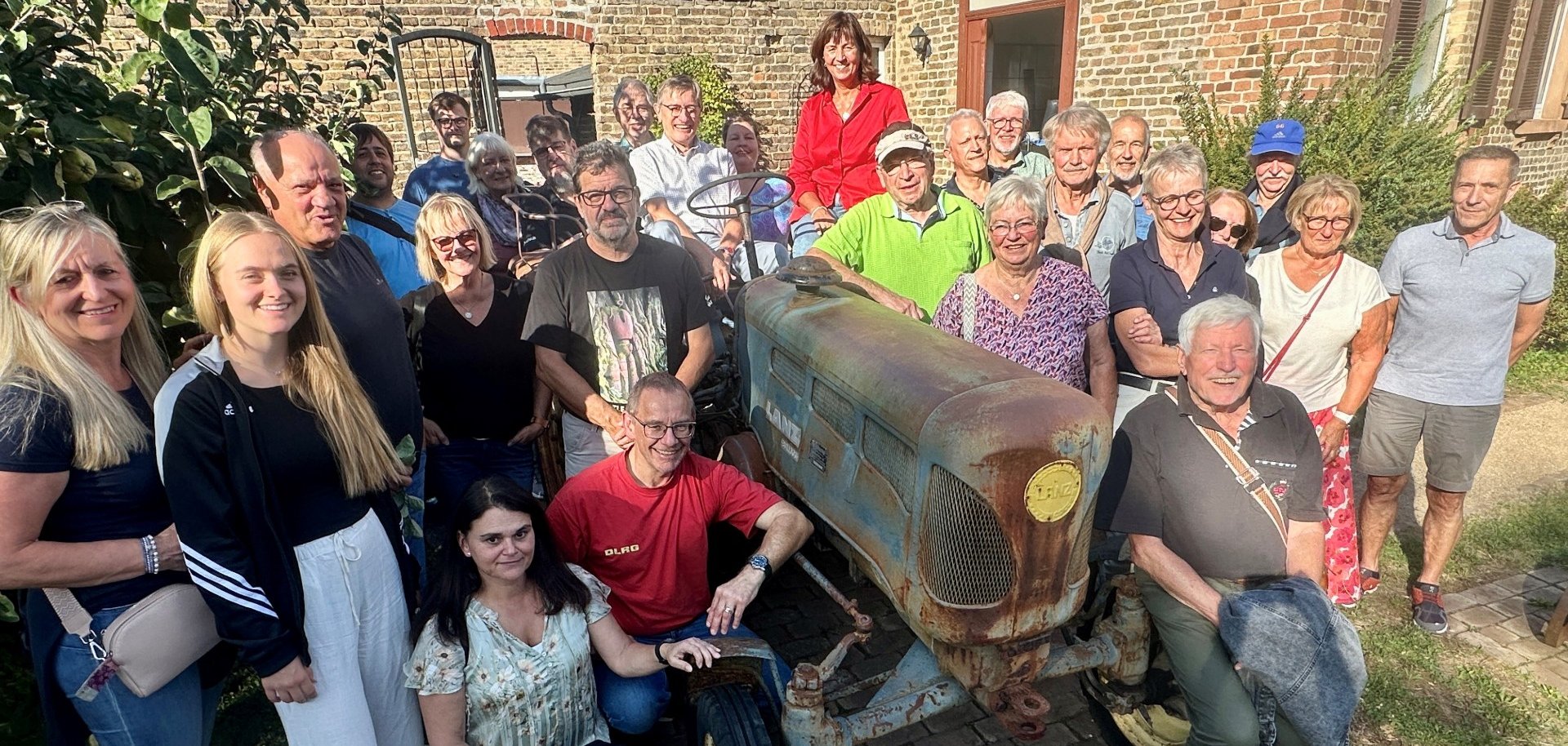 Fröhliche Helfergruppe rund um einen alten Traktor.