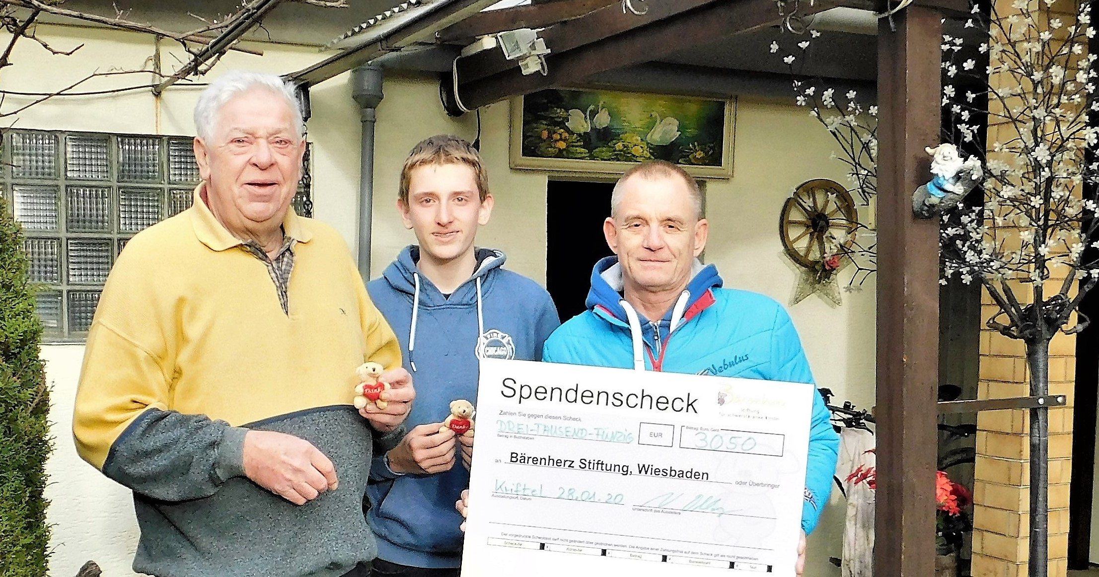 Daubitz, sein Enkel und Volker Oblong von Bärenherz mit einem Riesenscheck..