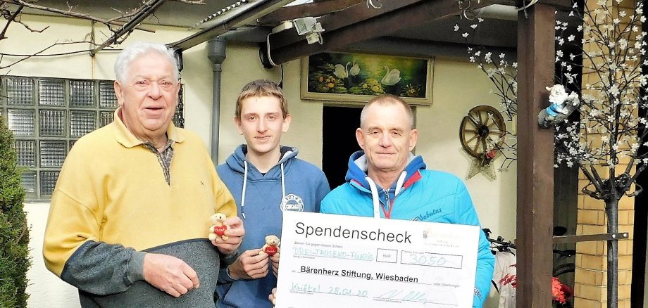 Daubitz, sein Enkel und Volker Oblong von Bärenherz mit einem Riesenscheck..