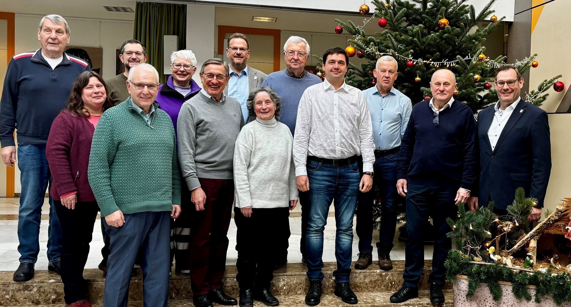 Die Delegationen mit Gastgebenden vor dem Tannenbaum im Rathaus.