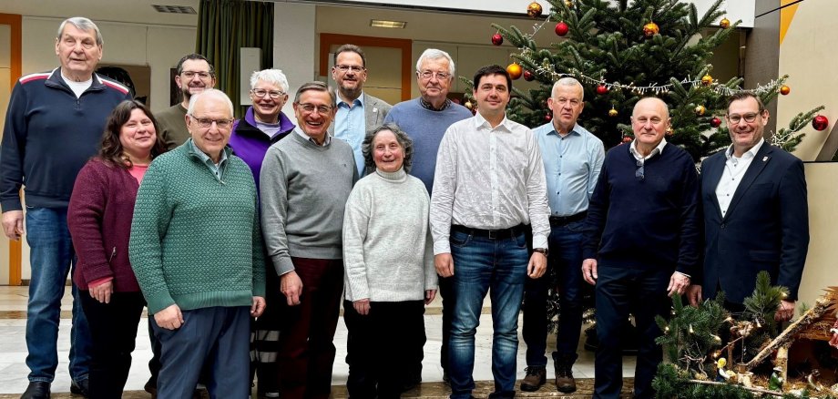 Die Delegationen mit Gastgebenden vor dem Tannenbaum im Rathaus.