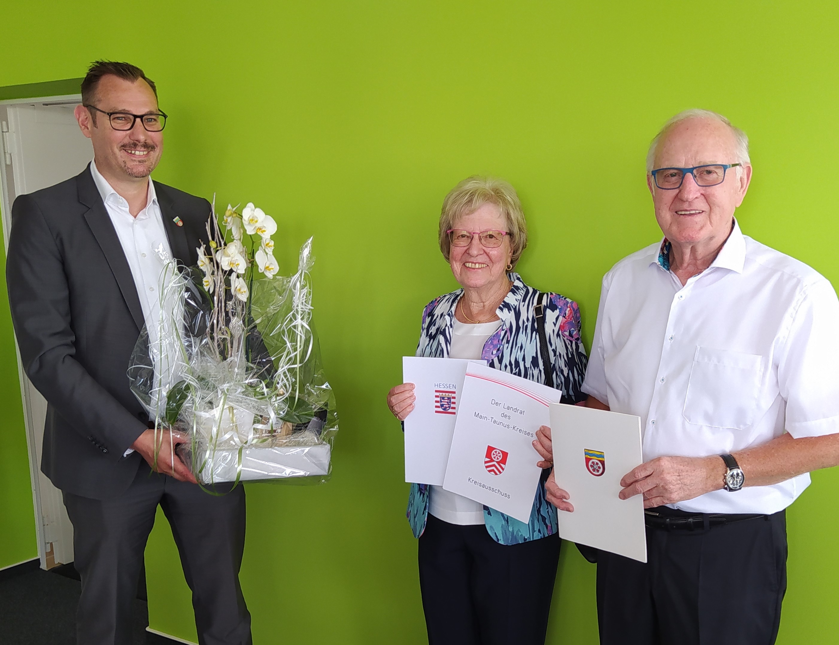 Ehepaar Klug mit Bürgermeister Seitz vor einer grünen Wand.