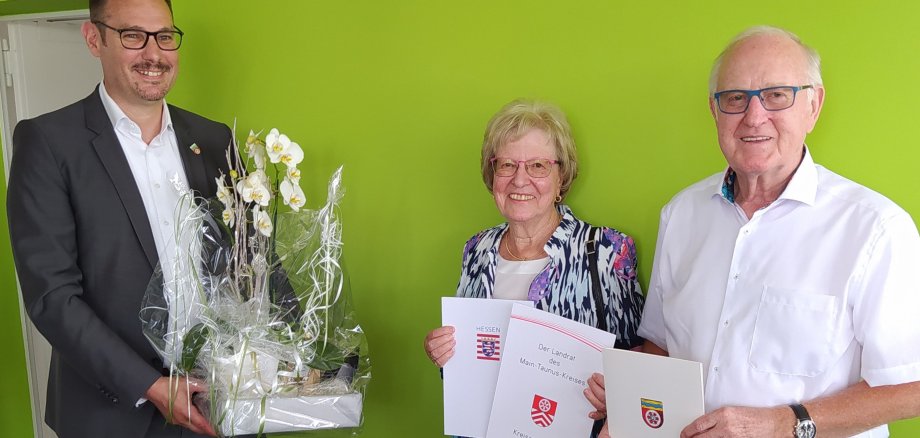 Ehepaar Klug mit Bürgermeister Seitz vor einer grünen Wand.
