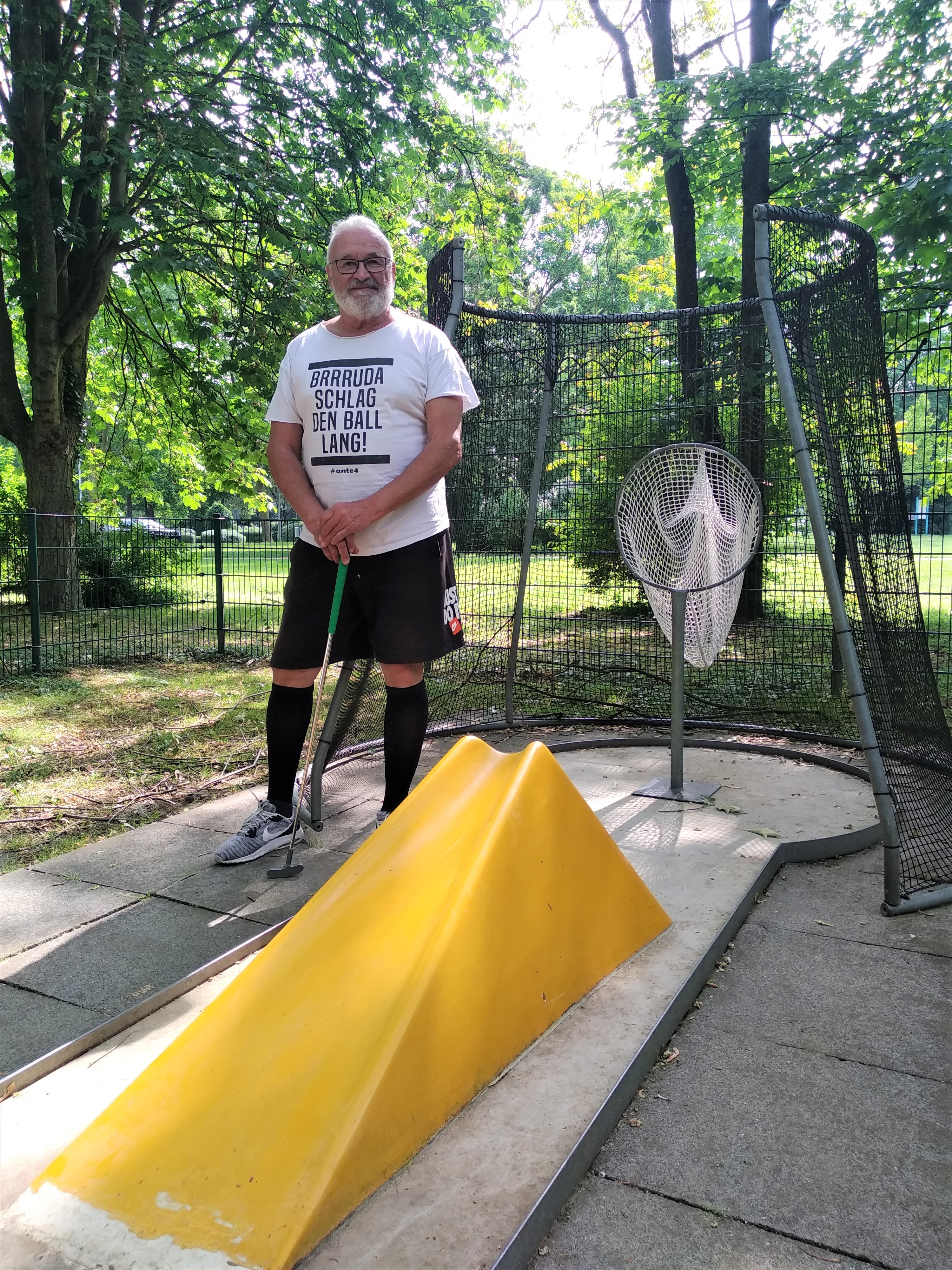 Dieter Veit mit Schläger neben einer Minigolf-Bahn.