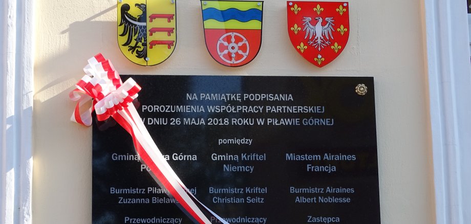 Die Gedenktafel mit den drei Wappen der drei Partnerstädte Airaines, Kriftel und Pilawa Gorna.